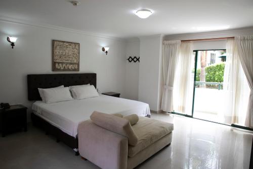 1 dormitorio con 1 cama, 1 silla y 1 ventana en Hotel Palmera Real, en Bucaramanga