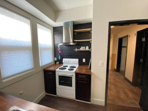 a kitchen with a white stove top oven next to two windows at Brand New 1 Br 1 Bath Close To All Walkable in Edmonton