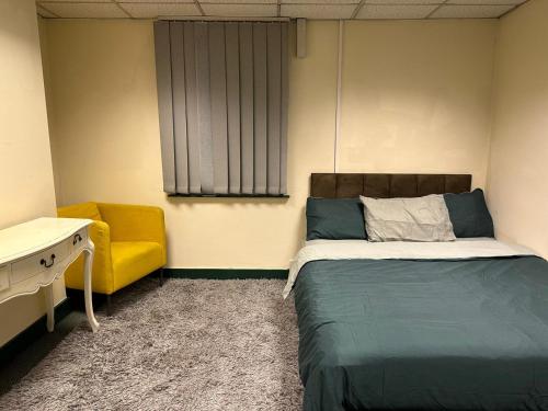 um quarto com uma cama e uma cadeira amarela em Grandma’s House em Walsall