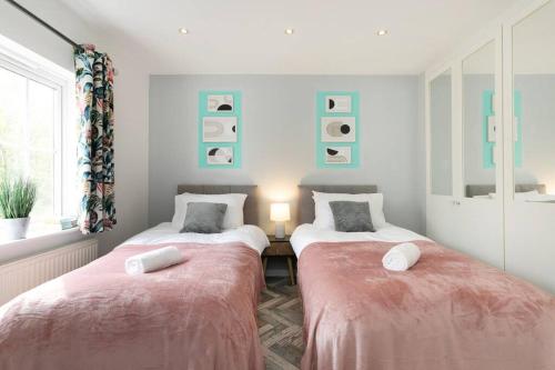 2 camas en una habitación con mantas rosas en Detached house with BIG monthly discount!, en Peterborough