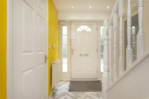 pasillo con puerta blanca y paredes amarillas en Detached house with BIG monthly discount!, en Peterborough