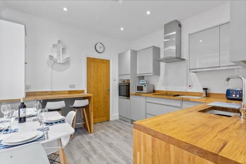 a kitchen with white cabinets and a table and chairs at Captain's Quarters in Hythe