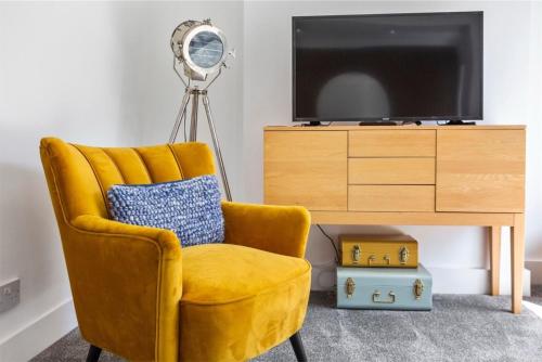 a yellow chair in a living room with a television at Captain's Quarters in Hythe