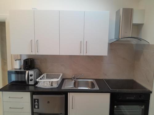 a kitchen with white cabinets and a sink at ND'S APARTMENT in Phibblestown