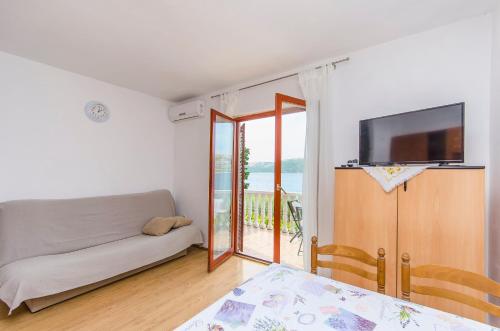 a living room with a couch and a television at Apartments Seafront Jadranka in Stara Novalja
