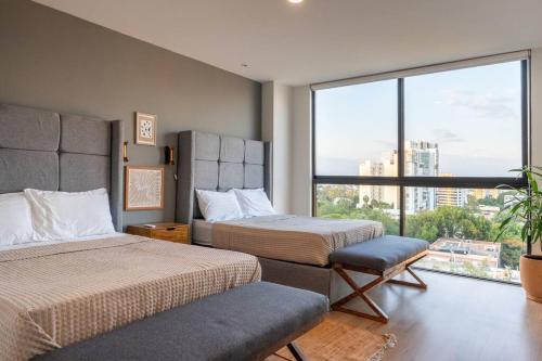 a hotel room with two beds and a large window at Amazing view with RoofGarden in Guadalajara