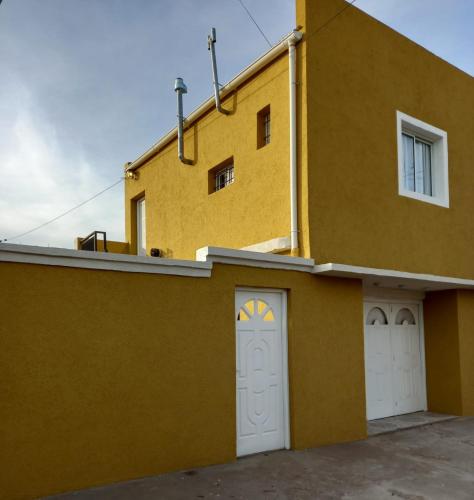 un bâtiment jaune avec deux portes de garage blanches dans l'établissement Santa Rosa LA PAMPA, à Santa Rosa
