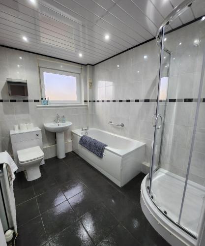 y baño con bañera, aseo y lavamanos. en FM Homes & Apartments 3 Bedroom Motherwell, en Motherwell