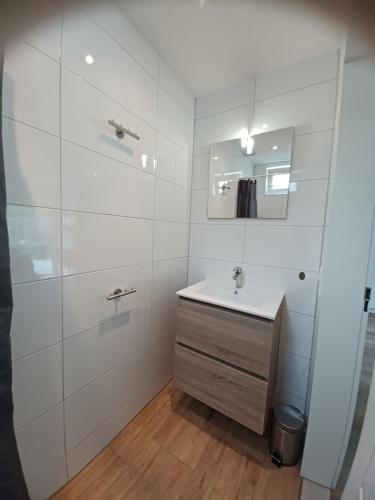 a white bathroom with a sink and a mirror at Bosweg 9a, Comfortabele vakantiewoning, Centrum Zoutelande in Zoutelande