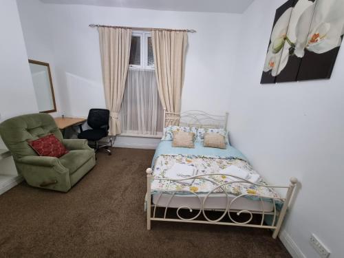 een slaapkamer met een bed, een stoel en een raam bij Spacious Flat Near Rochdale Centre Self Check-in Free Parking & Fast Wi-Fi in Rochdale