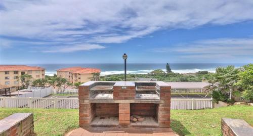 a brick fireplace with a view of the ocean at Illovo Beach View Apartment at Illovo Views in Kingsburgh