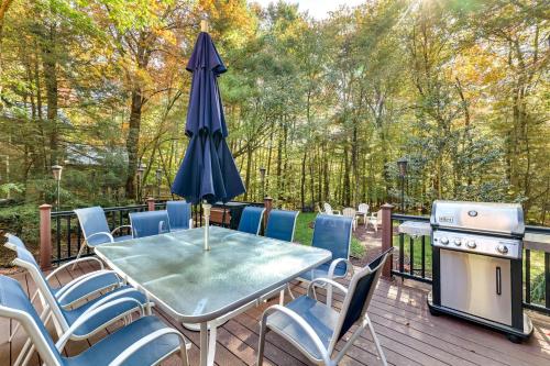 ein Tisch und Stühle auf einer Terrasse mit Sonnenschirm in der Unterkunft Pocono Pines Gem with Fire Pit and On-Site Creek! in Pocono Pines