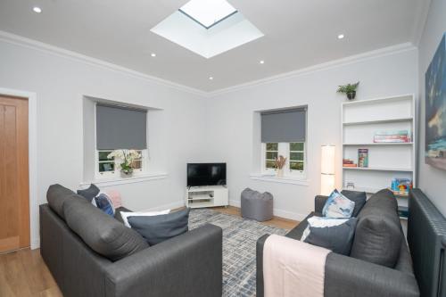a living room with two couches and a tv at Historical Holmehill Lodge in Dunblane
