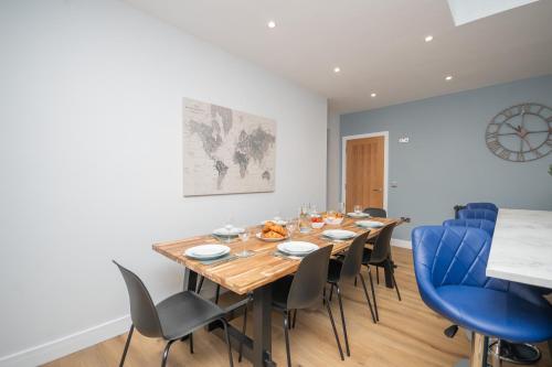 a dining room with a wooden table and blue chairs at Historical Holmehill Lodge in Dunblane