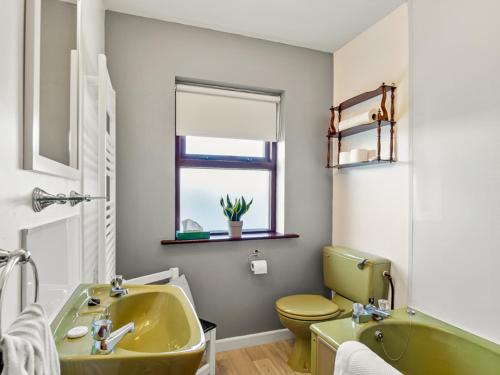 een badkamer met een gele wastafel en een toilet bij Flaherty Cottage in Ballyconneely