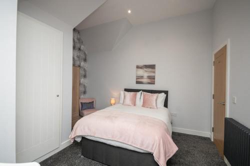 a bedroom with a large bed with pink pillows at Historical Holmehill Lodge in Dunblane