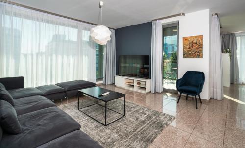 a living room with a couch and a tv at Vertigo Modern 2-Bedroom Apartment with Parking & Vitosha View in Sofia