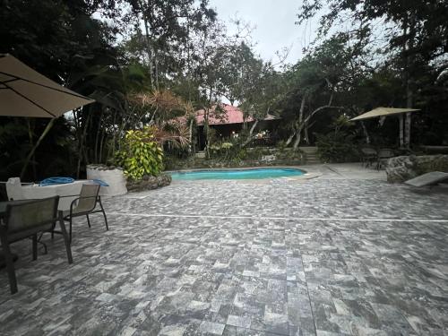 a patio with a swimming pool with chairs and an umbrella at Samai Lodge Holistic Living in Olón