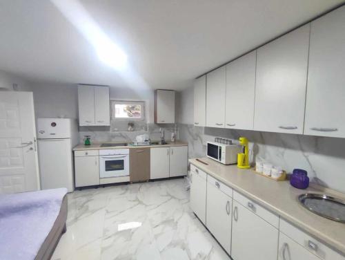 a kitchen with white cabinets and white appliances at Apartments Janiki in Kruševo