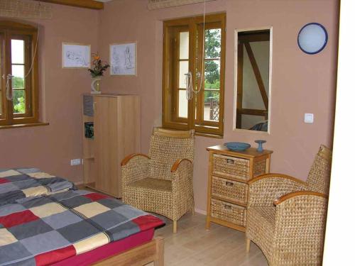a bedroom with a bed and two chairs and a dresser at In der alten Weinstube in Freital