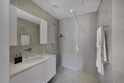 a white bathroom with a sink and a shower at Marina 107 in Cape Town