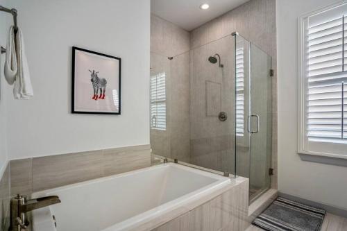 y baño con bañera y ducha acristalada. en Urban Jungle Retreat in the HTX Skyline, en Houston