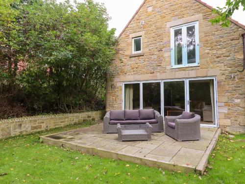 a patio with couches and chairs in front of a house at Quarry Haven in Bamburgh