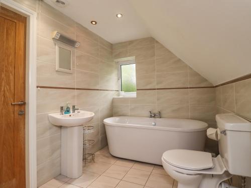 a bathroom with a toilet and a tub and a sink at Quarry Haven in Bamburgh