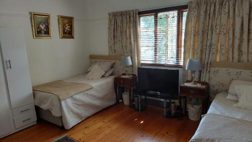 1 dormitorio con 2 camas y TV. en Glenette Residence, en Ciudad del Cabo