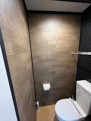 a bathroom with a toilet and a wooden wall at Lucky Hotel in Tokyo