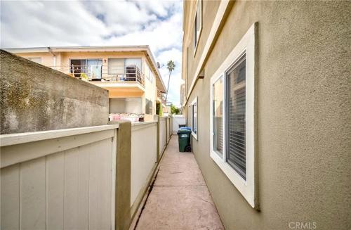 a narrow alley between two buildings with a green trash can at Shared Luxury Beach house in Redondo Beach. Private 2 Bedrooms / Bath in Redondo Beach