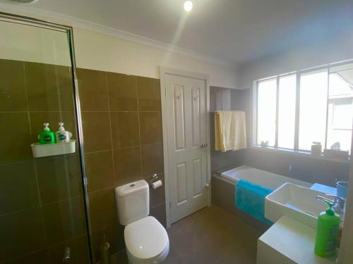 a bathroom with a toilet and a tub and a sink at Seaside Sanctuary Port Noarlunga in Port Noarlunga South