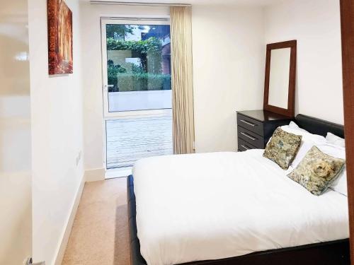 1 dormitorio con cama blanca y ventana en Your Riverside Home 2 with Private balcony, en Woolwich