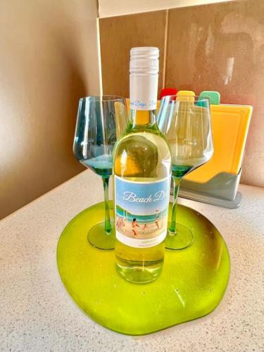 a bottle of wine sitting on a counter with two wine glasses at Seaside Sanctuary Port Noarlunga in Port Noarlunga South