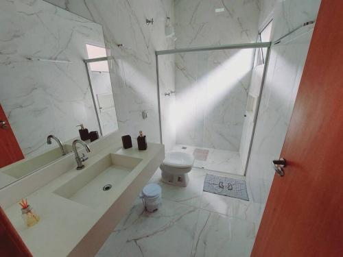 a bathroom with a sink and a toilet and a shower at Casa de Temporada Maju - Olímpia - SP in Olímpia