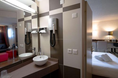 a bathroom with a sink and a mirror and a bed at Best Western l'Atelier 117 in Maubeuge