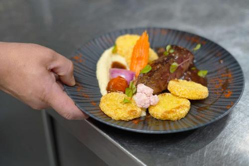 a person holding a blue plate with food on it at Best Western l'Atelier 117 in Maubeuge