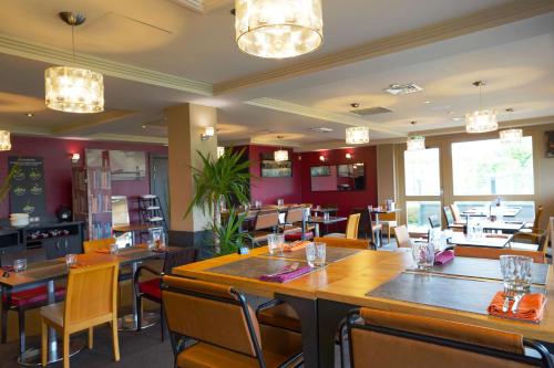 a dining room with tables and chairs and a restaurant at Best Western l'Atelier 117 in Maubeuge