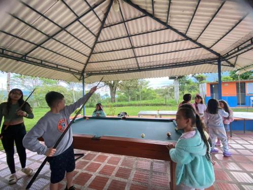 a boy and girl playing pool under a tent at Finca La perla in Pavas