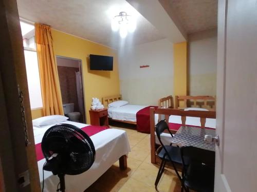 a room with two beds and a table and a fan at Hotel los angeles in Huaral