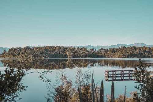 a view of a lake with trees and a dock at Lake Mahinapua Hotel in Ruatapu