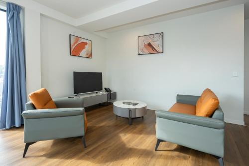 a living room with two chairs and a television at The Edgerley Suites in Auckland