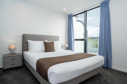 a bedroom with a large bed and a large window at The Edgerley Suites in Auckland
