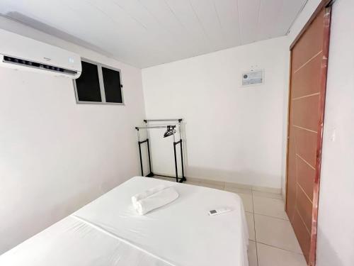 um pequeno quarto branco com uma cama e uma janela em Apartamento Simples e completo em Maragogi
