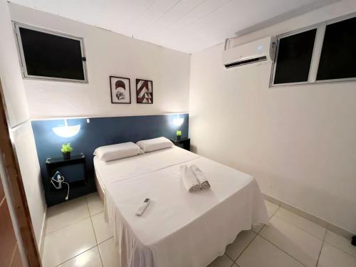 um quarto com uma cama branca e uma televisão em Apartamento Simples e completo em Maragogi