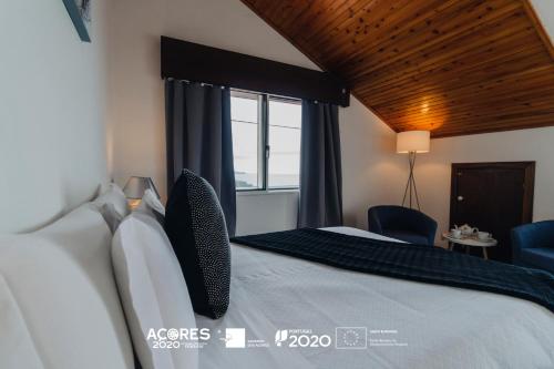 a bedroom with a large bed with a window at Miradouro da Papalva Guest House - Pico - Azores in São João