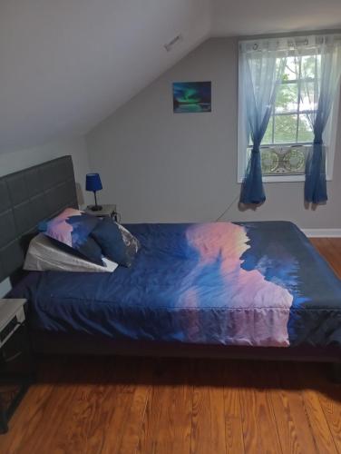 ein Schlafzimmer mit einem Bett mit blauer Decke und einem Fenster in der Unterkunft Cozy Suburban Nest in Hopewell