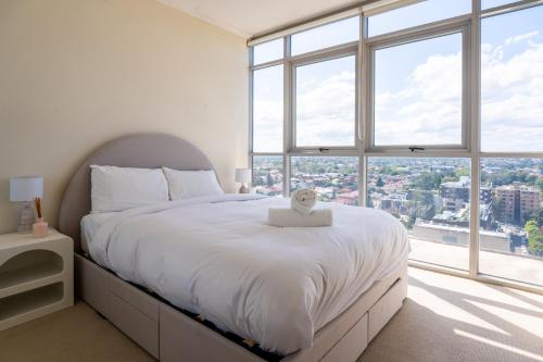a bedroom with a large bed with a large window at Burwood 1bedroom Apartment next to Station in Sydney