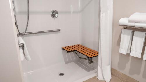 a bathroom with a shower with a wooden bench in it at Holiday Inn Express Hotel & Suites Newton Sparta by IHG in Newton