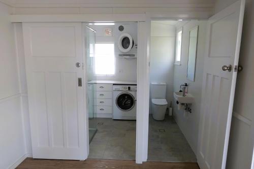 a white bathroom with a washing machine and a washer at Christina Cottage in South West Rocks